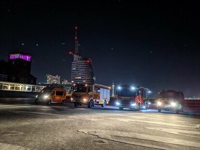 Fahrzeuge der Freiwilligen Feuerwehr Bremerhaven-Lehe vor der Skyline Bremerhavens bei Nacht